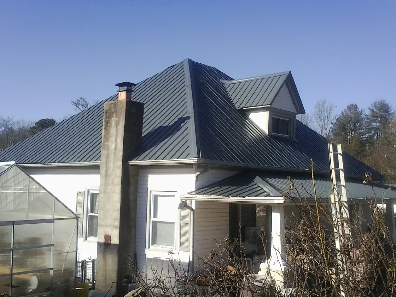 Dark blue standing seam metal roof on a white farmhouse with dormer — Slate & Tile Roof Repair by Roofing Brothers in Baldwin